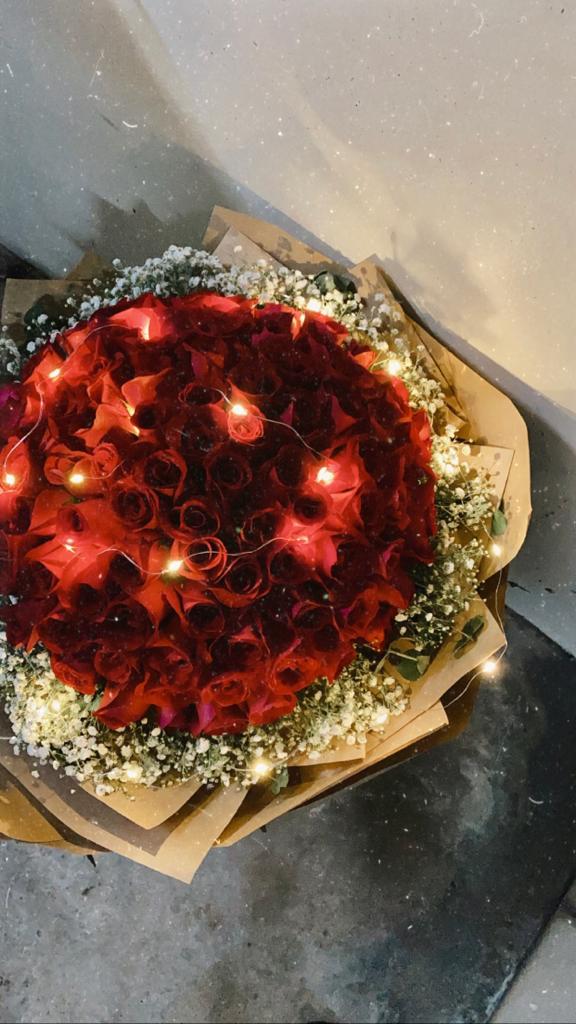 Romantic 99 roses bouquet with red roses, baby’s breath, and fairy lights, beautifully wrapped in kraft paper – perfect for expressing grand love gestures in Singapore.